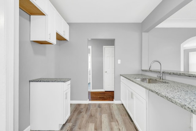 13955 Prevost St, Detroit, MI 48227 - kitchen with baseboards, light wood-type flooring, light stone counters, white cabinetry, and a sink