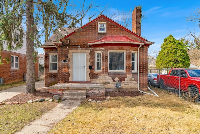 13955 Prevost St, Detroit, MI 48227 - bungalow-style home with a front yard, metal roof, a chimney, fence, and brick siding