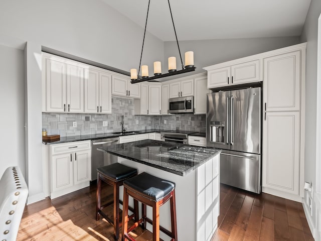 kitchen featuring a kitchen island, white cabinets, a sink, appliances with stainless steel finishes, and backsplash