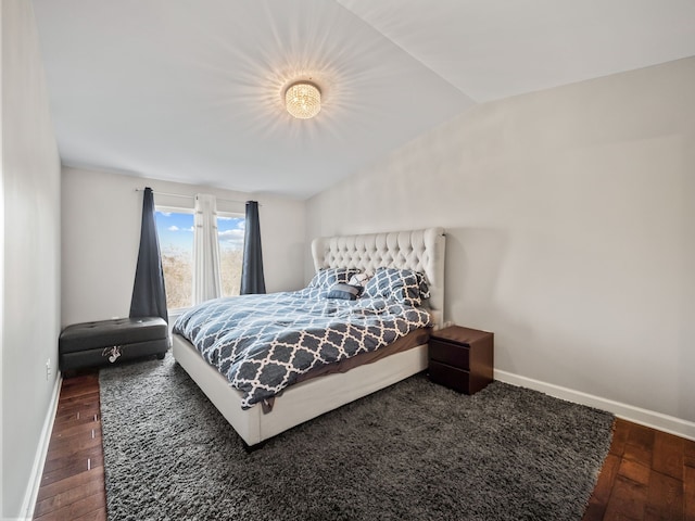 bedroom with baseboards, wood finished floors, and lofted ceiling