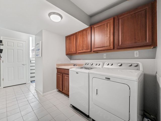laundry room with cabinet space, light tile patterned floors, a sink, baseboards, and washer and clothes dryer