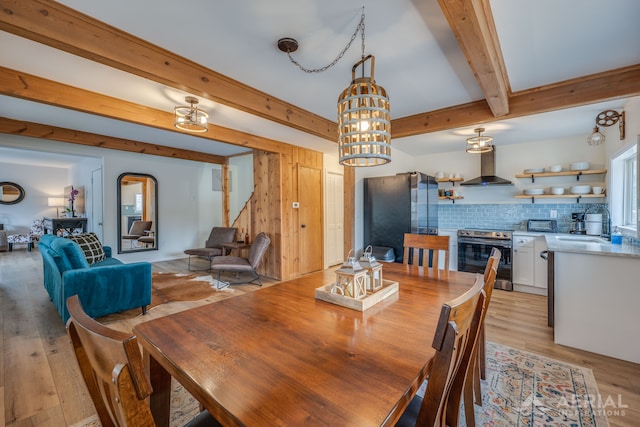 dining room featuring beamed ceiling and light wood finished floors