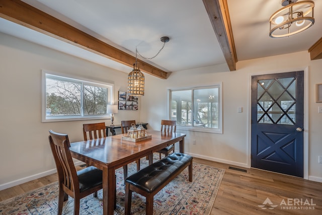 dining space featuring light wood finished floors, baseboards, beam ceiling, and visible vents
