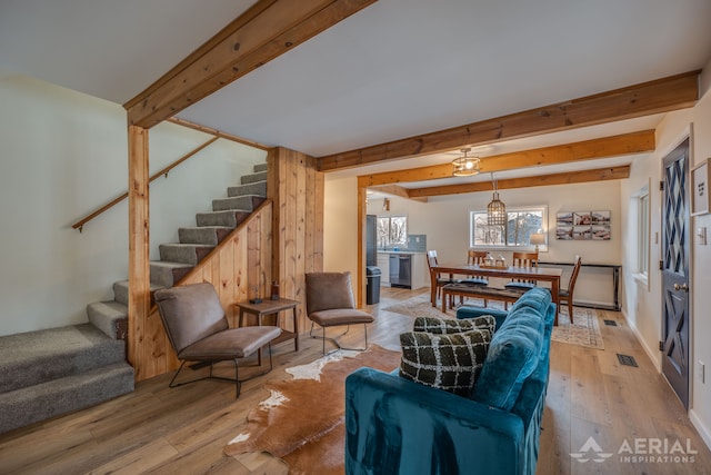 living room featuring beam ceiling, wood finished floors, and stairs