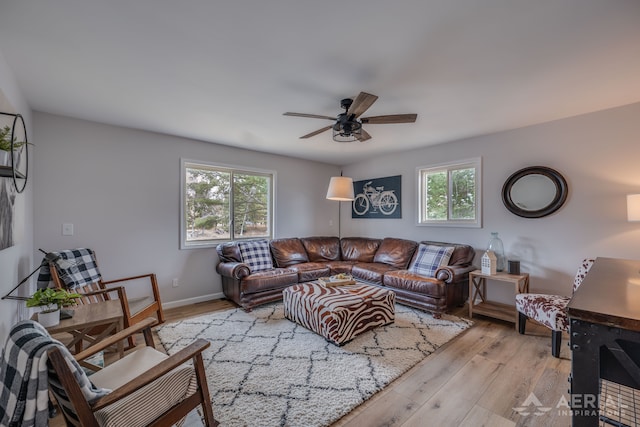 living room featuring light wood-type flooring, a wealth of natural light, baseboards, and ceiling fan