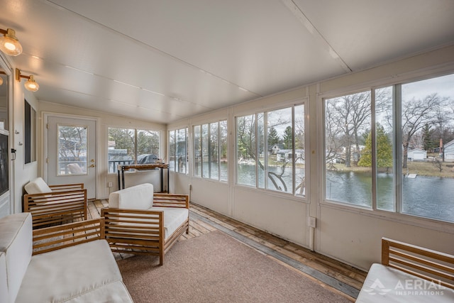 sunroom with lofted ceiling, hardwood / wood-style floors, an outdoor hangout area, and a water view