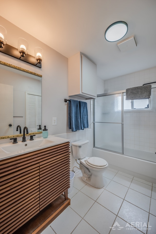 full bathroom with tile patterned floors, vanity, combined bath / shower with glass door, and toilet