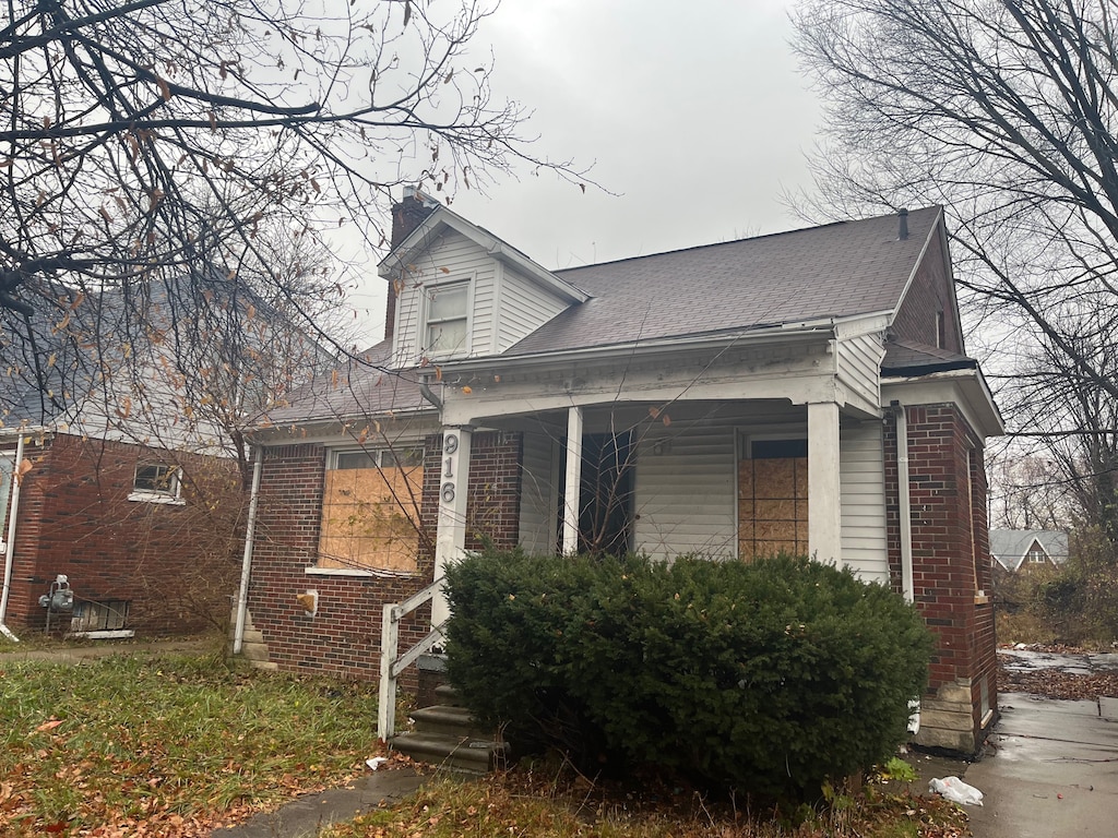 9166 Guilford St, Detroit, MI 48224 - view of home's exterior with a porch, a chimney, and brick siding