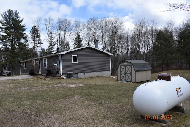 view of side of home with a storage shed, a lawn, an outdoor structure, and central AC