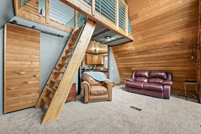 9341 W M-115, Mesick, MI 49668 - carpeted living room featuring wood walls, stairs, visible vents, and a barn door