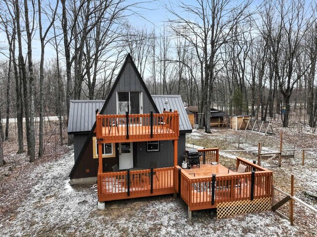 9341 W M-115, Mesick, MI 49668 - snow covered back of property featuring a standing seam roof, metal roof, and a deck