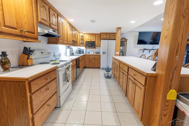 kitchen with visible vents, brown cabinets, light tile patterned floors, under cabinet range hood, and white appliances