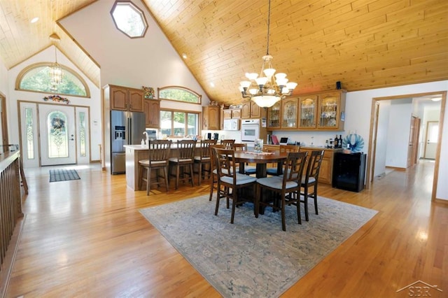 dining room with light wood-style floors, high vaulted ceiling, and a chandelier