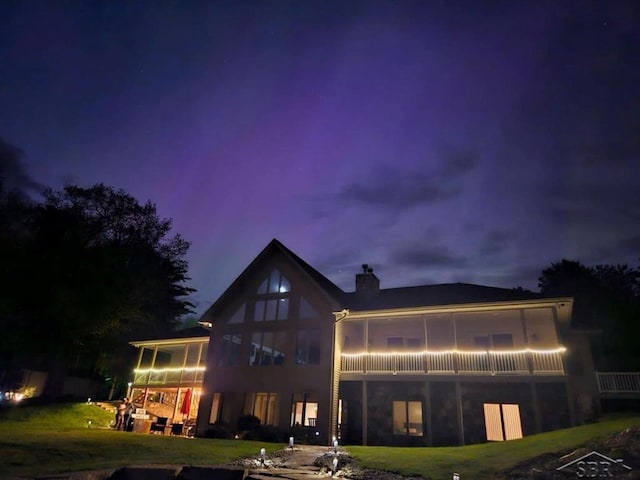 back of house with a yard, a chimney, and a sunroom