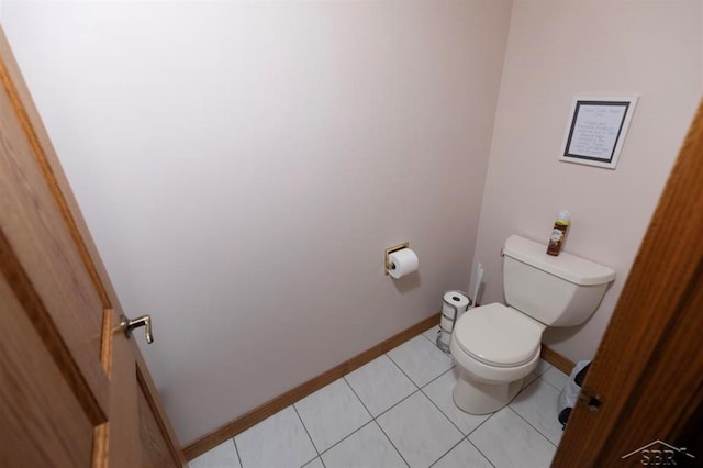 bathroom with toilet, baseboards, and tile patterned flooring