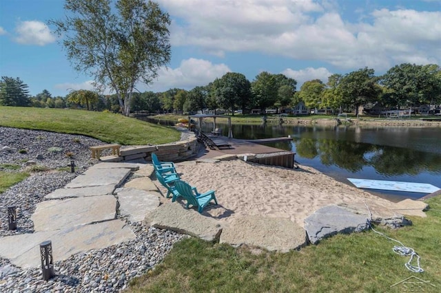 view of home's community with a lawn, a water view, and a boat dock