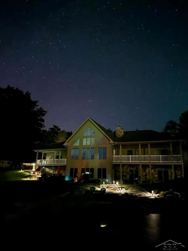 back of house at twilight with a balcony