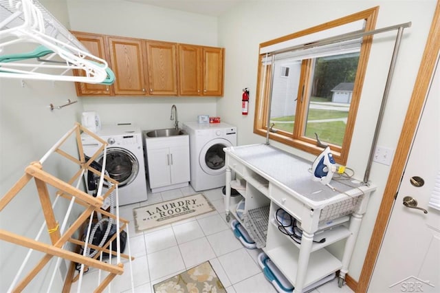washroom featuring cabinet space, light tile patterned floors, a sink, and washing machine and clothes dryer