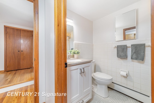 1804 Ardmore St, Midland, MI 48642 - bathroom with baseboard heating, tile walls, toilet, vanity, and a wainscoted wall