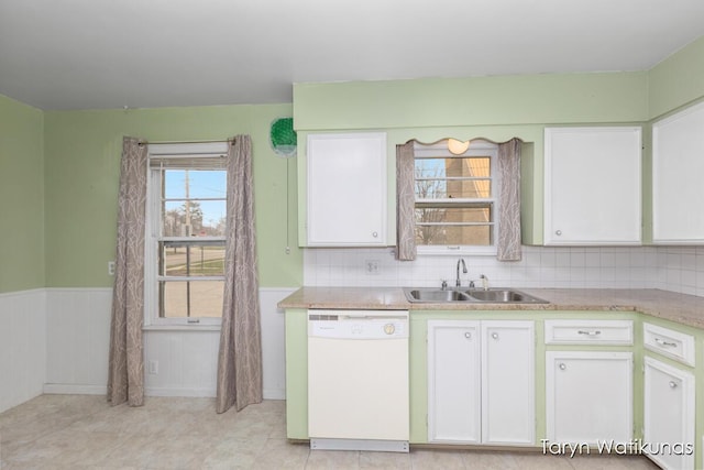 1193 E Apple Ave, Muskegon, MI 49442 - kitchen with dishwasher, a sink, light countertops, white cabinetry, and a wainscoted wall