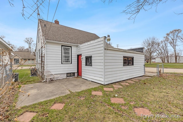 1193 E Apple Ave, Muskegon, MI 49442 - rear view of property with a lawn, roof with shingles, a patio area, fence, and a chimney