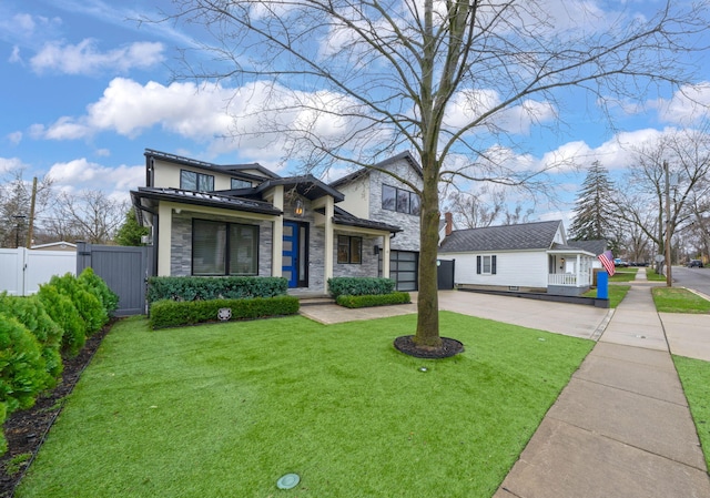 view of front of property with a gate, stone siding, fence, a front lawn, and driveway