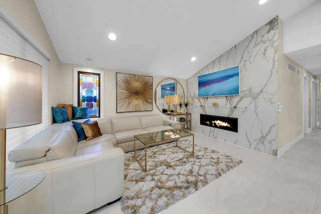 living room featuring a premium fireplace, visible vents, lofted ceiling, and recessed lighting