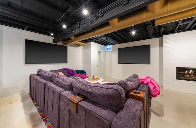 cinema room featuring finished concrete flooring, baseboards, and a glass covered fireplace