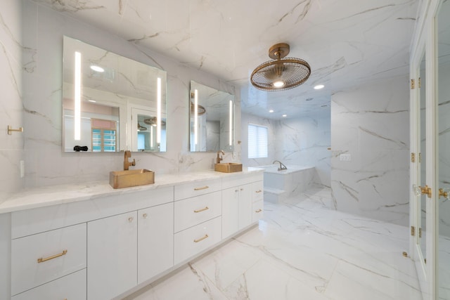 full bath with double vanity, marble finish floor, a sink, and stone wall
