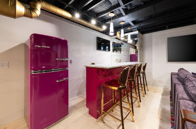 bar with wet bar, concrete floors, refrigerator, and baseboards