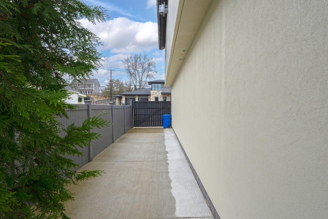 view of side of property with fence, a gate, and stucco siding