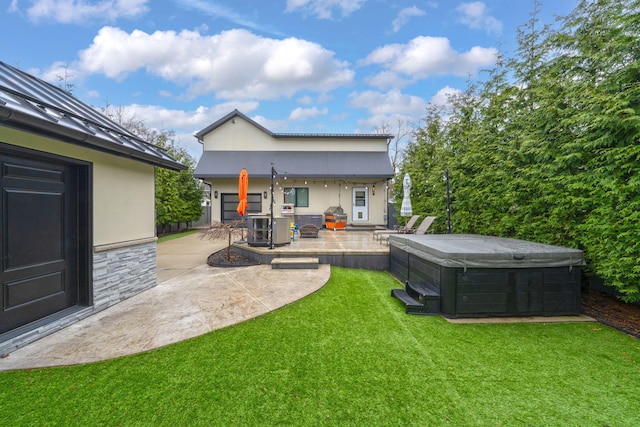 back of property with a hot tub, a patio area, stone siding, a lawn, and stucco siding
