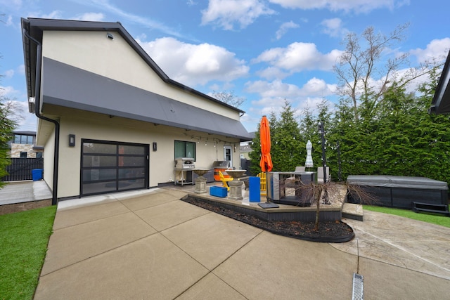 exterior space with area for grilling, concrete driveway, a garage, and a hot tub