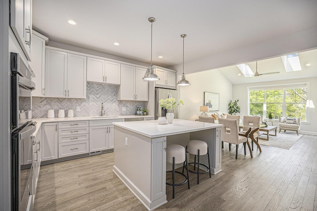3092 N Spurway Dr, Ann Arbor, MI 48105 - kitchen featuring a skylight, a sink, appliances with stainless steel finishes, light wood finished floors, and tasteful backsplash