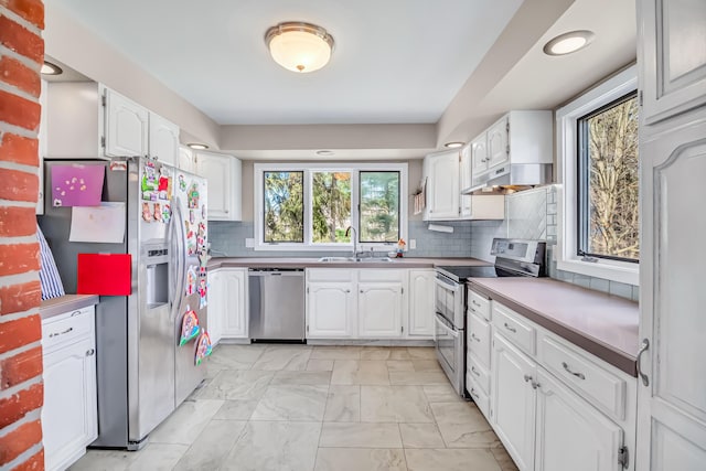 1856 N 56th Ave, Mears, MI 49436 - kitchen featuring appliances with stainless steel finishes, under cabinet range hood, white cabinets, backsplash, and light marble finish floors