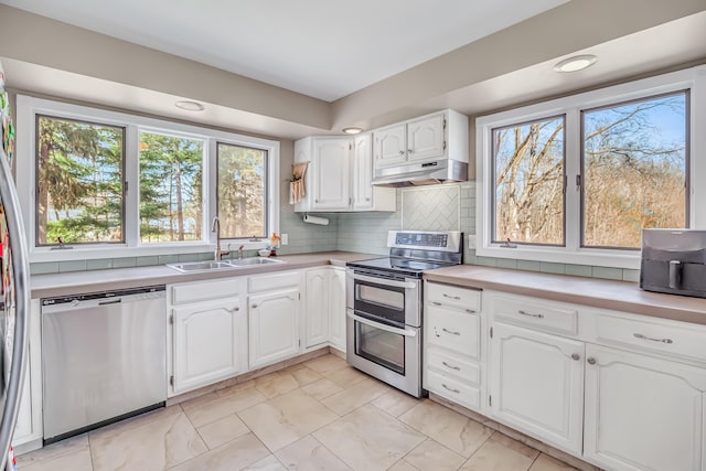 1856 N 56th Ave, Mears, MI 49436 - kitchen featuring appliances with stainless steel finishes, under cabinet range hood, light marble finish flooring, white cabinetry, and light countertops