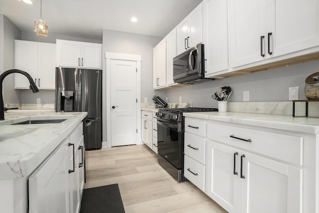 2128 Sampson Ave, Muskegon, MI 49441 - kitchen with stainless steel appliances, white cabinetry, recessed lighting, light wood-style flooring, and light stone countertops