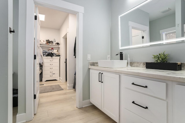 2128 Sampson Ave, Muskegon, MI 49441 - bathroom featuring vanity, wood finished floors, and a walk in closet