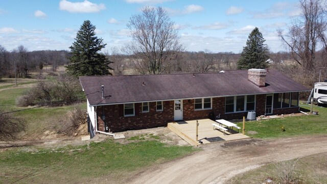 view of front of home featuring central AC unit, a chimney, a front yard, brick siding, and a sunroom