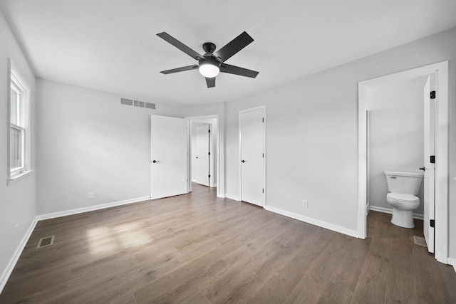 unfurnished bedroom featuring connected bathroom, baseboards, wood finished floors, and visible vents
