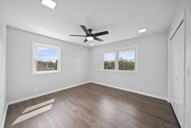 unfurnished bedroom featuring baseboards, dark wood-style flooring, multiple windows, and a closet