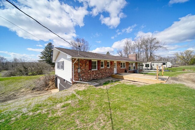 view of front of home featuring a chimney, a front lawn, a deck, a garage, and brick siding