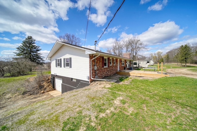 view of side of home featuring a chimney, a wooden deck, a lawn, brick siding, and a garage