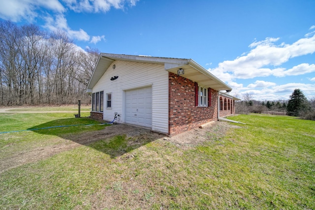view of home's exterior featuring brick siding, a yard, and driveway
