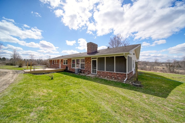 back of house with brick siding, a chimney, a yard, cooling unit, and a sunroom