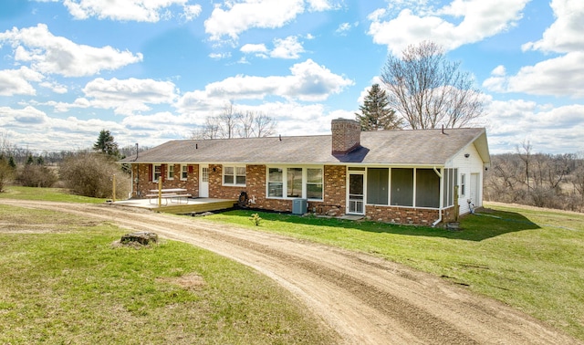 single story home featuring dirt driveway, a chimney, central air condition unit, brick siding, and a front yard