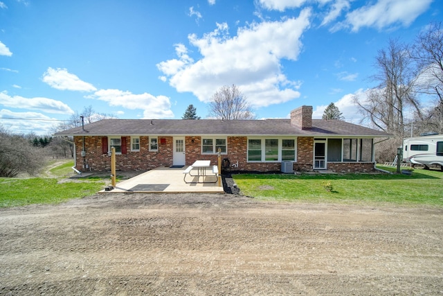 ranch-style home with brick siding, central air condition unit, a front lawn, and a chimney