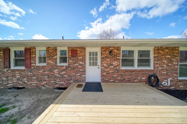 doorway to property with brick siding and a deck