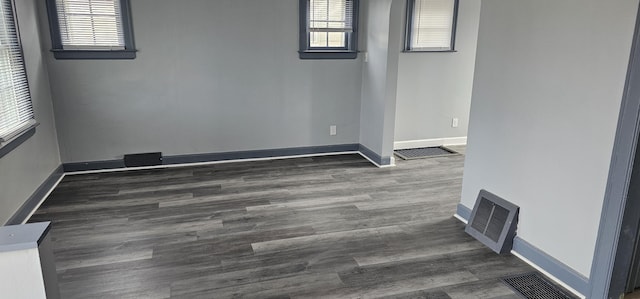 spare room with visible vents, baseboards, and wood finished floors