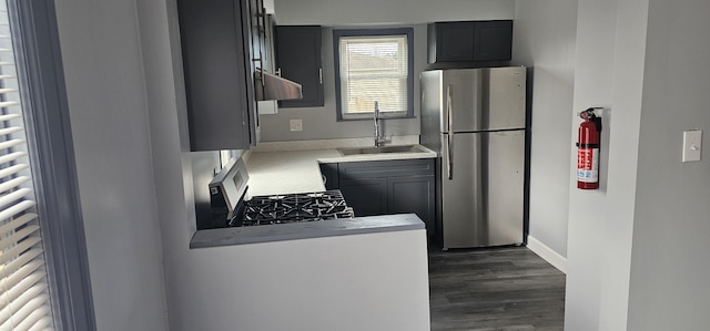 kitchen featuring dark wood-style flooring, light countertops, under cabinet range hood, appliances with stainless steel finishes, and a sink